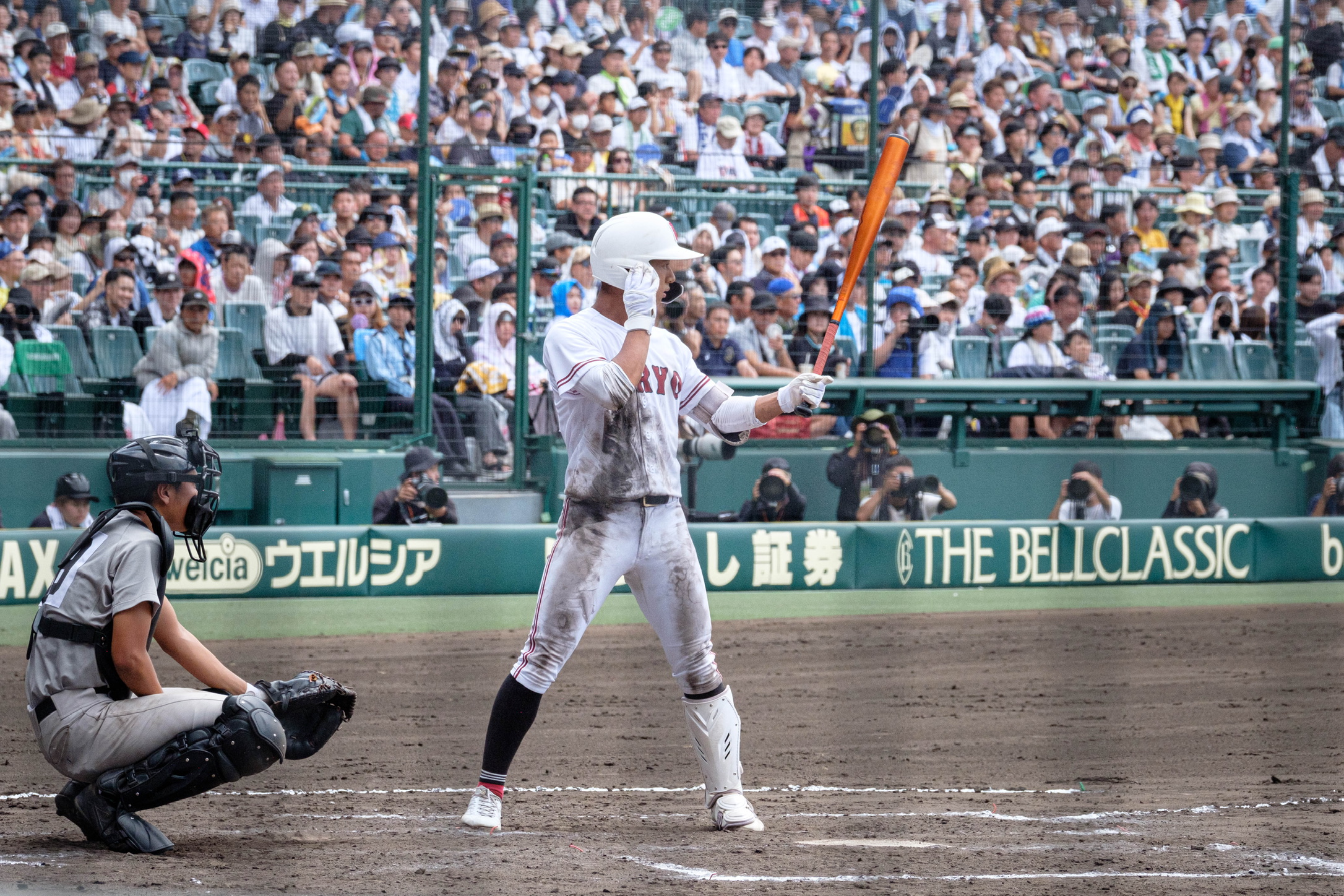 A batter waiting at the plate in a crowded stadium