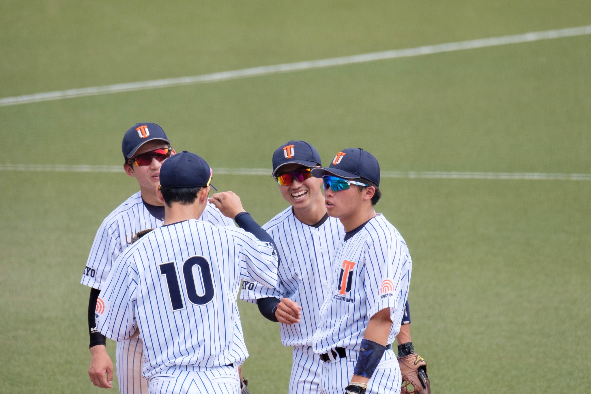 Four baseball players talking and smiling between plays