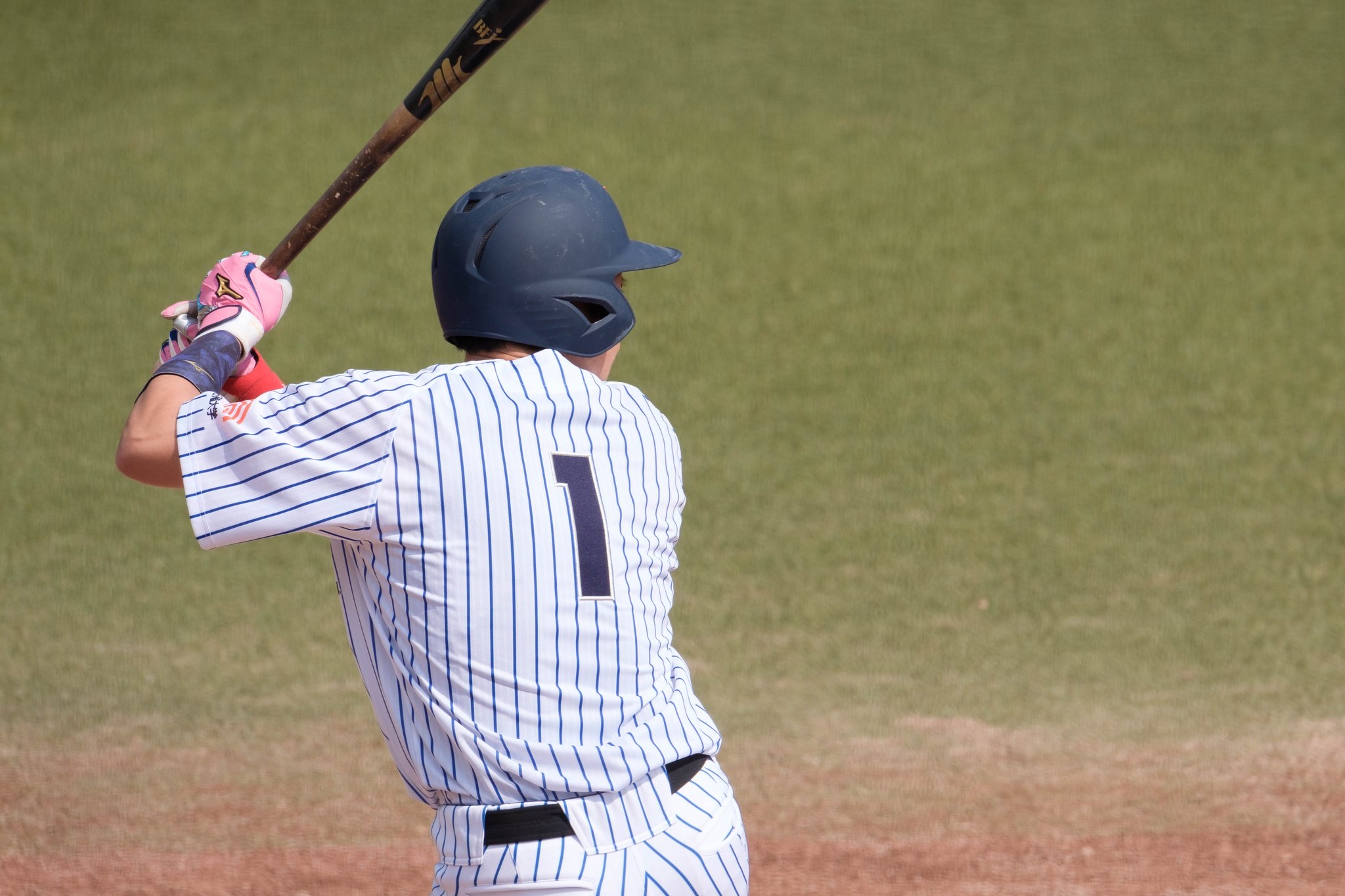 A baseball batter preparing to swing with the field behind him