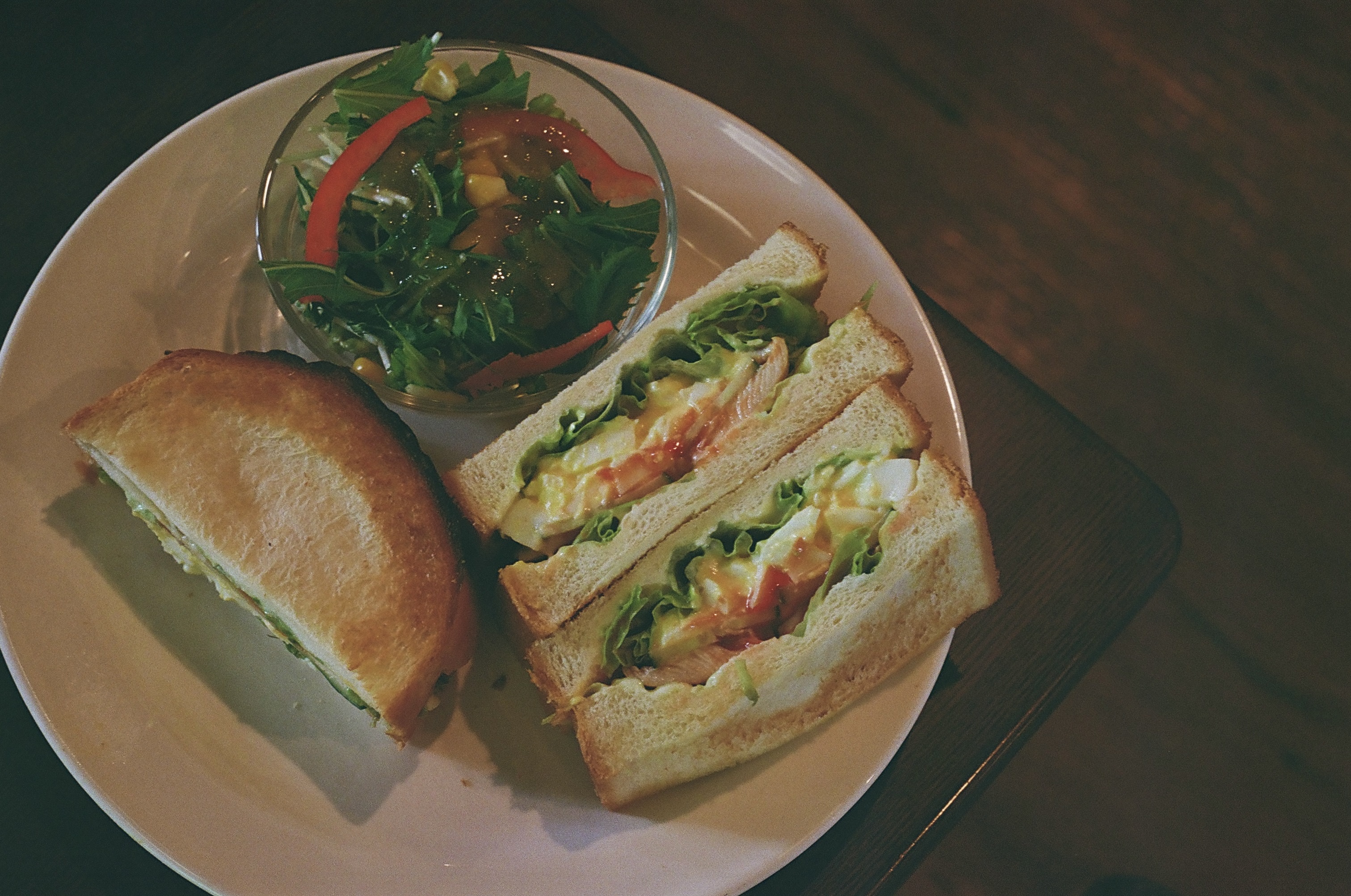 A sandwich and salad arranged on a wooden table