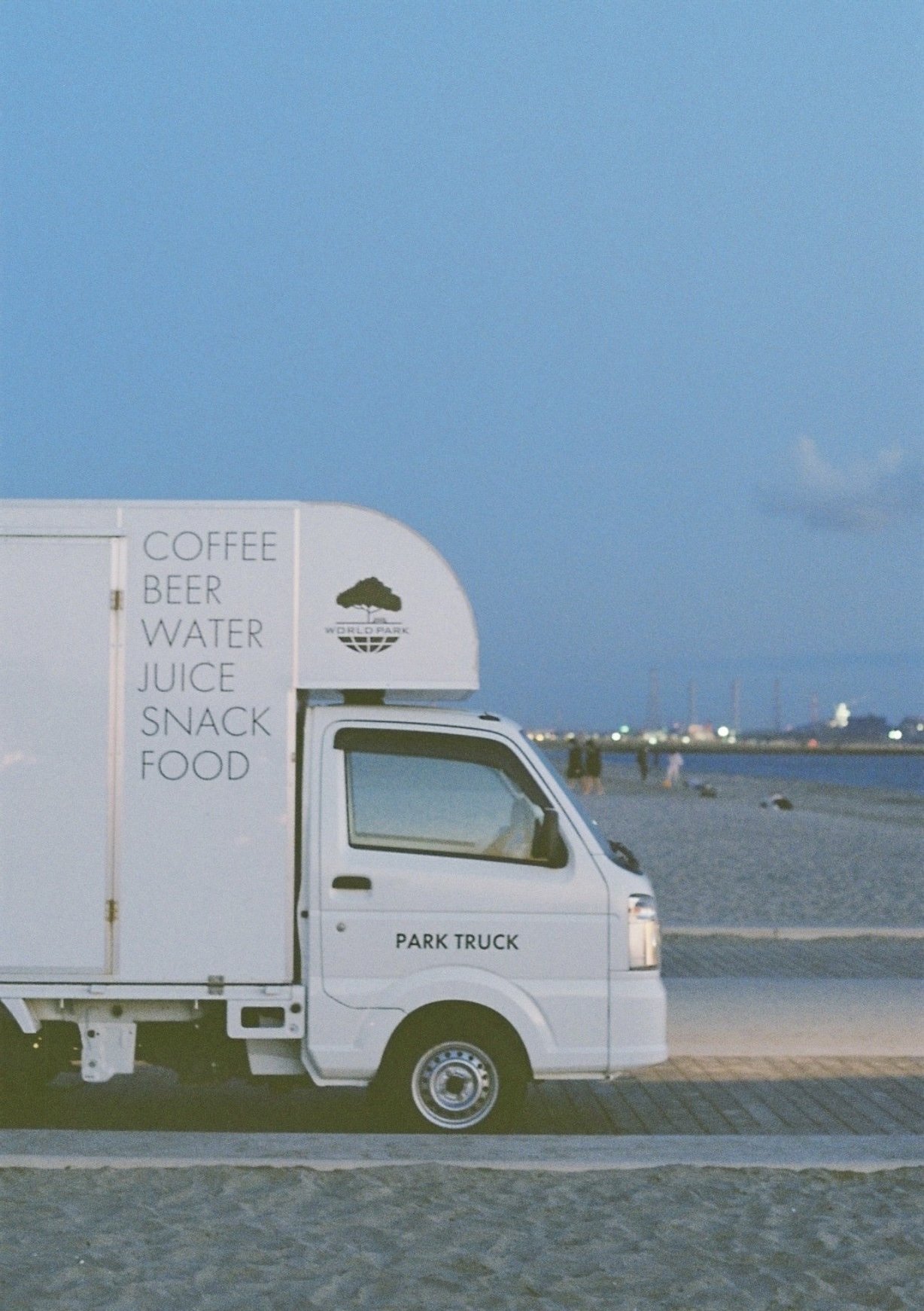 A food truck parked beside the coast beneath a clear sky
