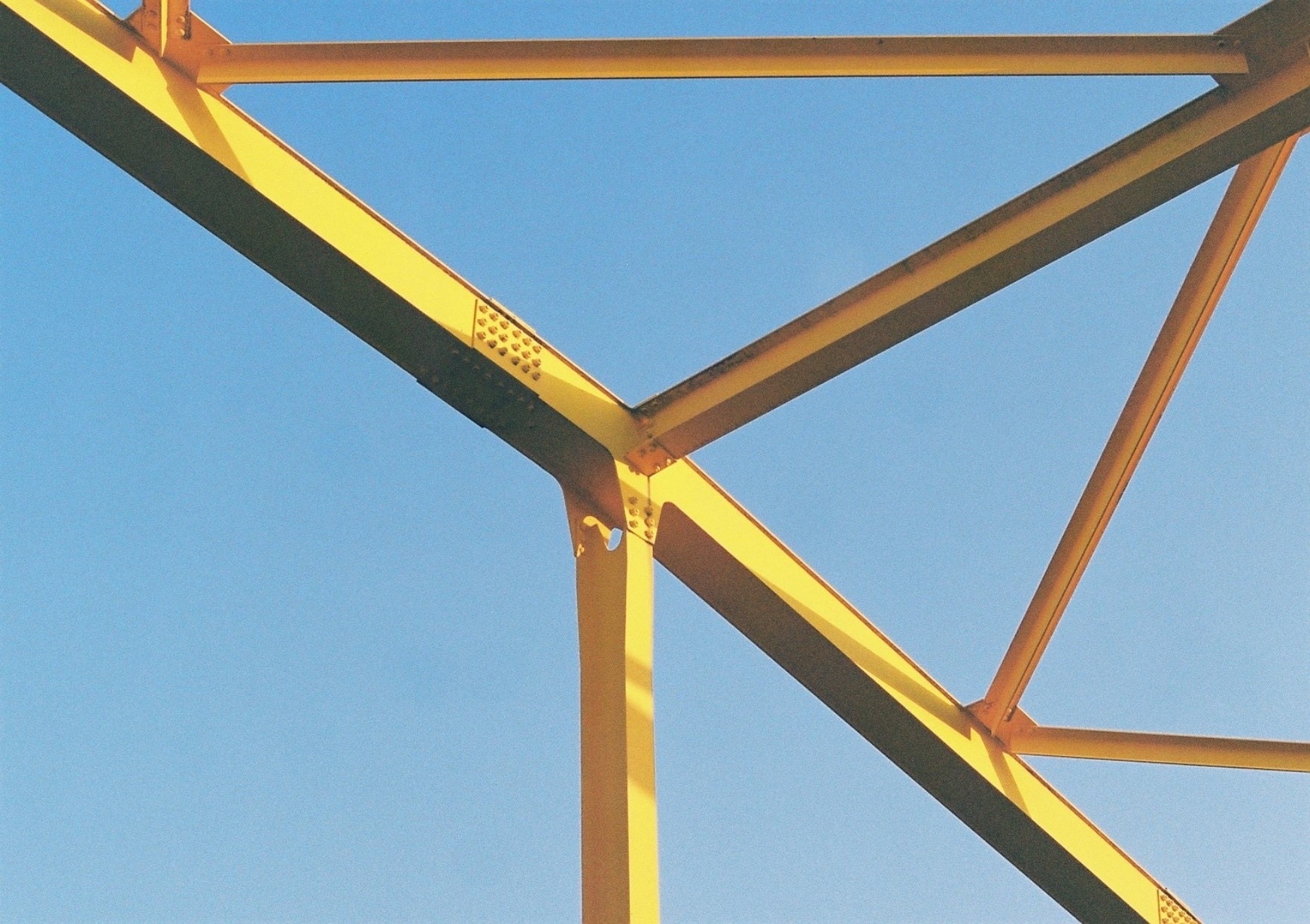 Yellow steel beams crossing a deep blue sky