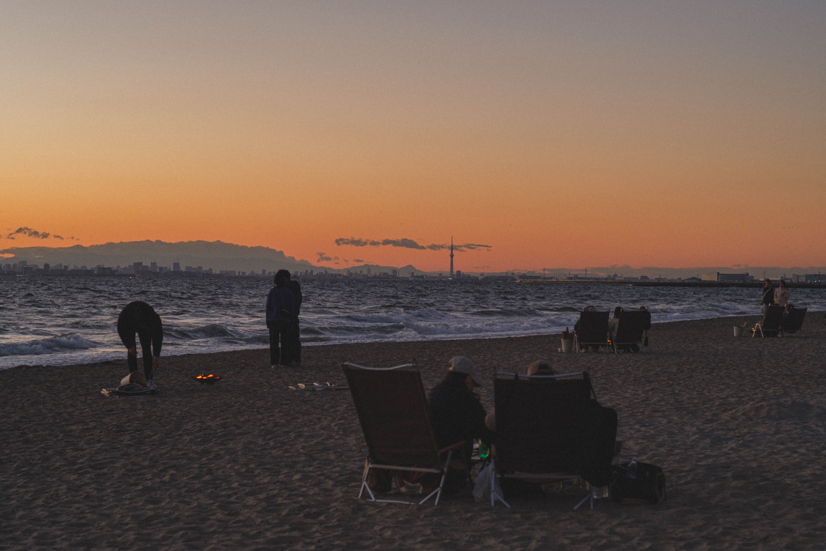 A dark beach beneath a soft orange evening sky