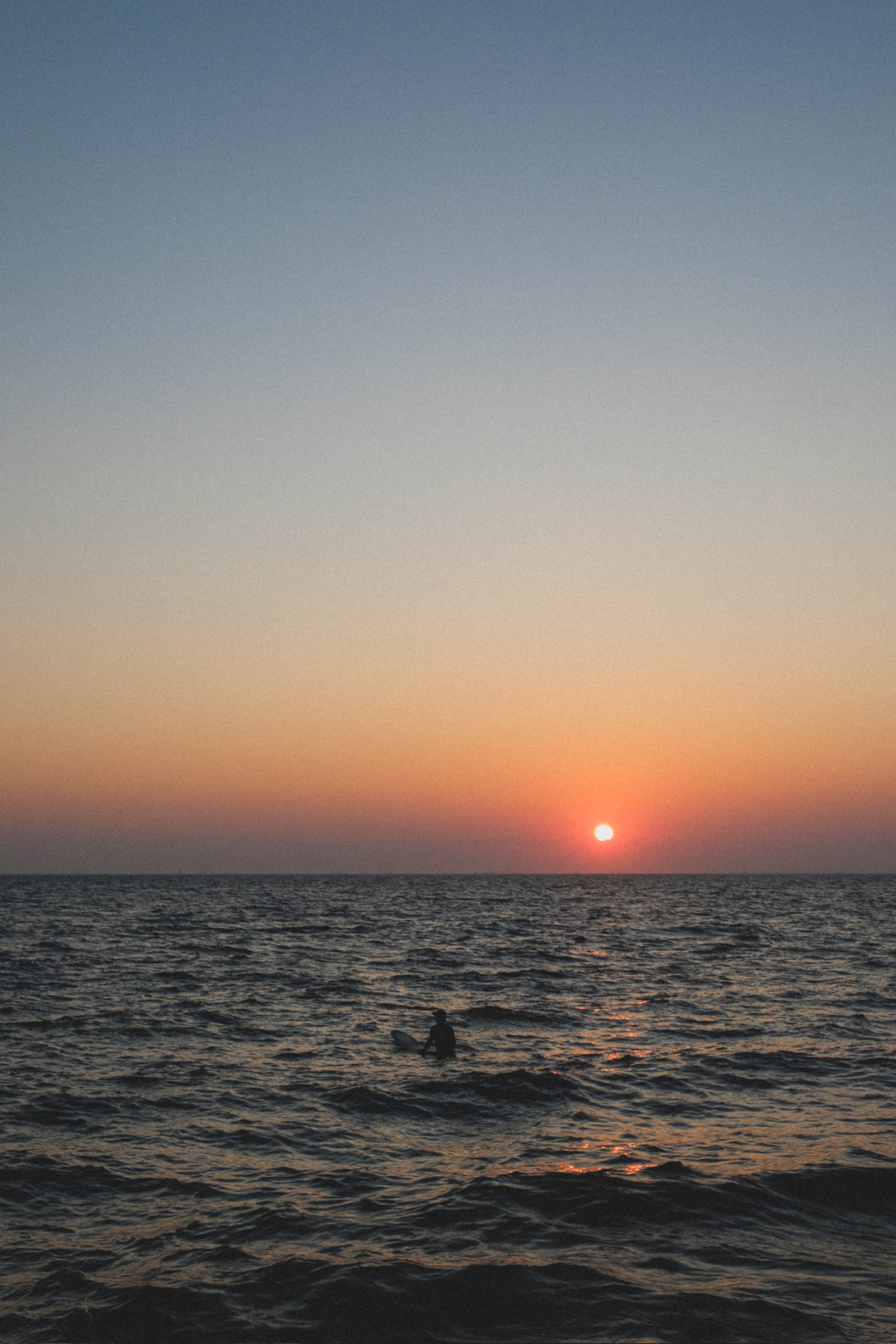 A swimmer silhouetted in the sea at sunset