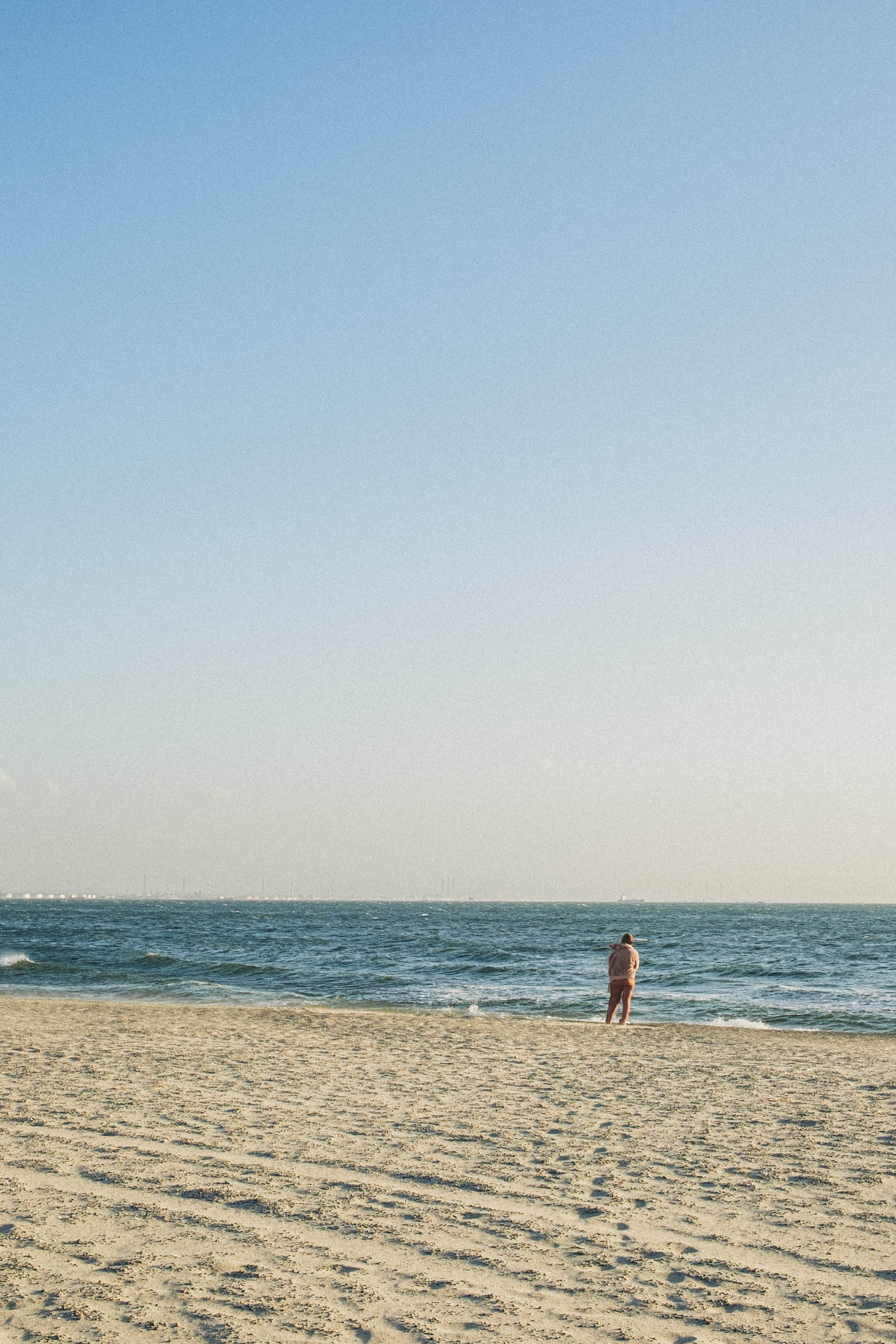 A solitary person standing on a bright open beach
